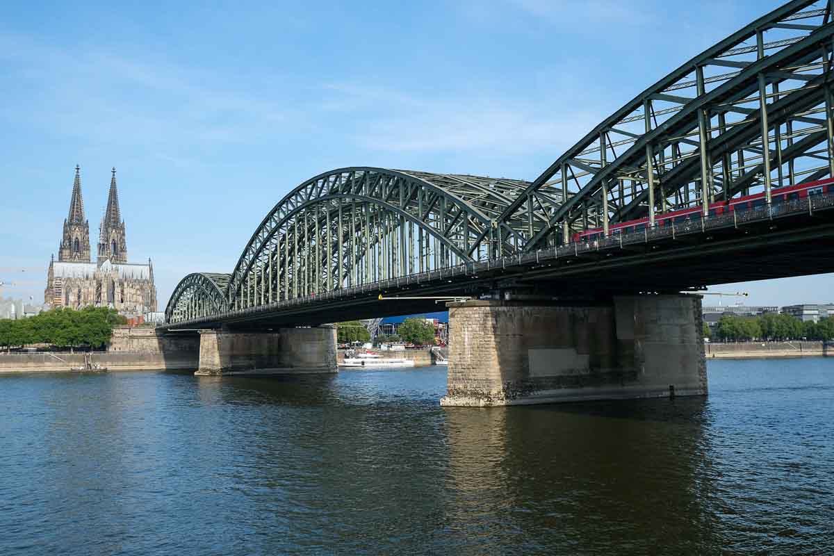 iron railway bridge over river with cologne cathedral in background