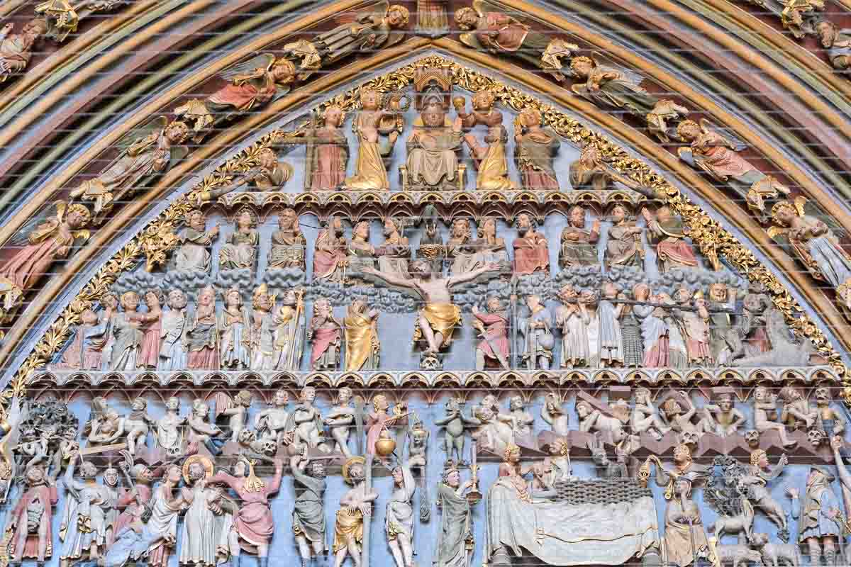intricate religious carvings above a doorway with a central crucifxion scene