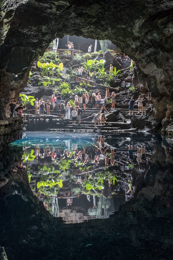 reflecting pool in a cave with lots of people and greenery