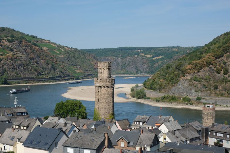 tall tower rising from the grey rooftops of a town on a bend in the river rhine germany