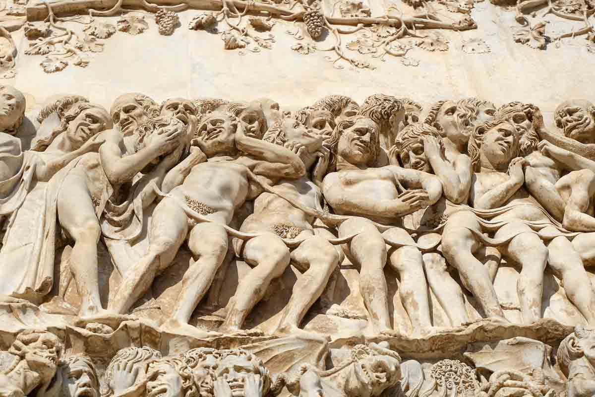 stone carings of a seriew of slightly grotesque figures on outside wall of cathedral in orvieto