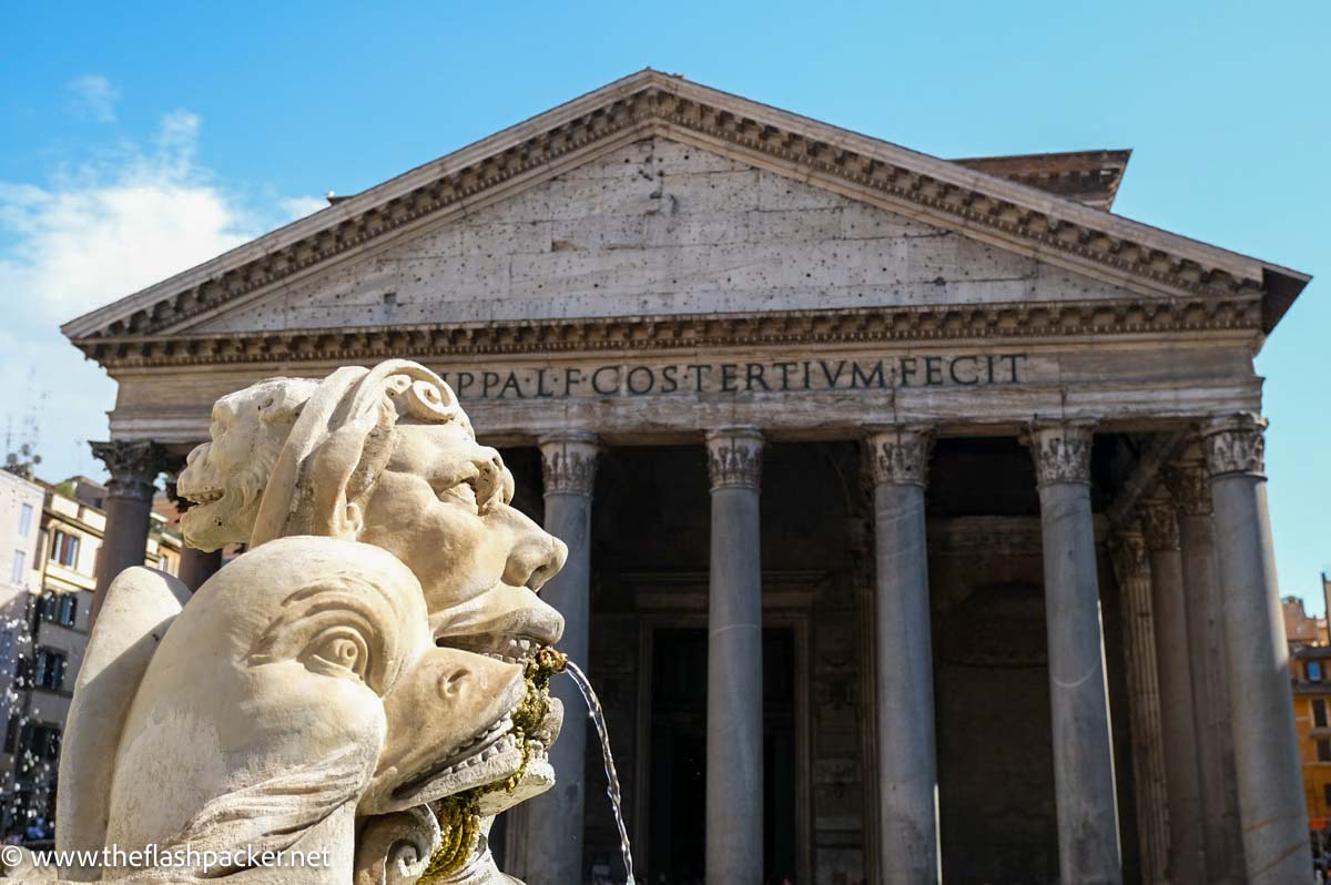 fountain spouting water in front of colonnaded facade of pantheon in rome italy