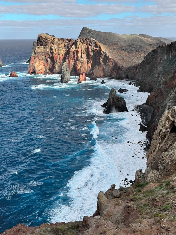 red and grey granite cliffs next to waves of ocean