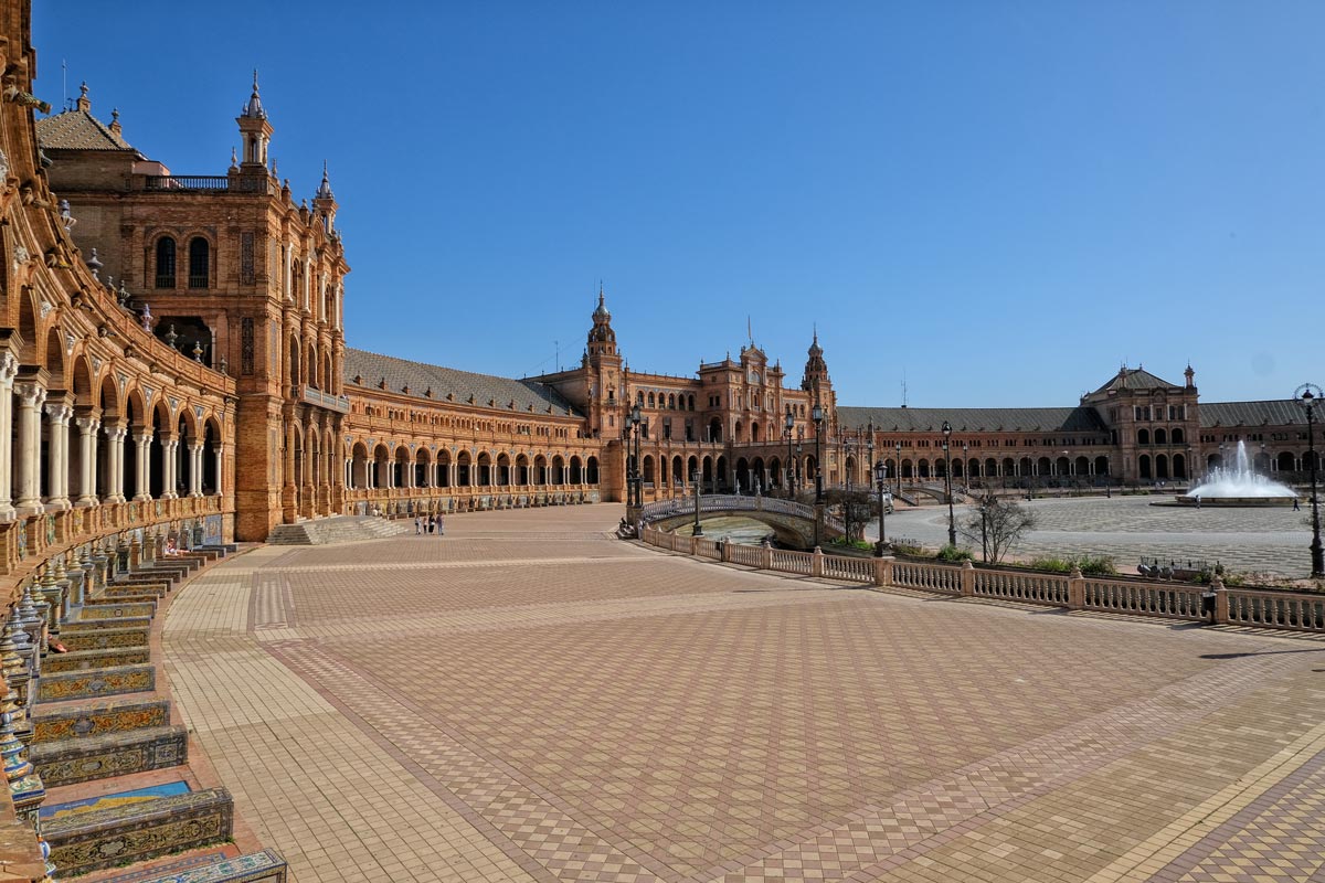 How to Get from Málaga to Seville by Train, Bus and Car 1 immense plaza with curved collonaded loggia and tiled plaques seen on a triop from málaga to seville