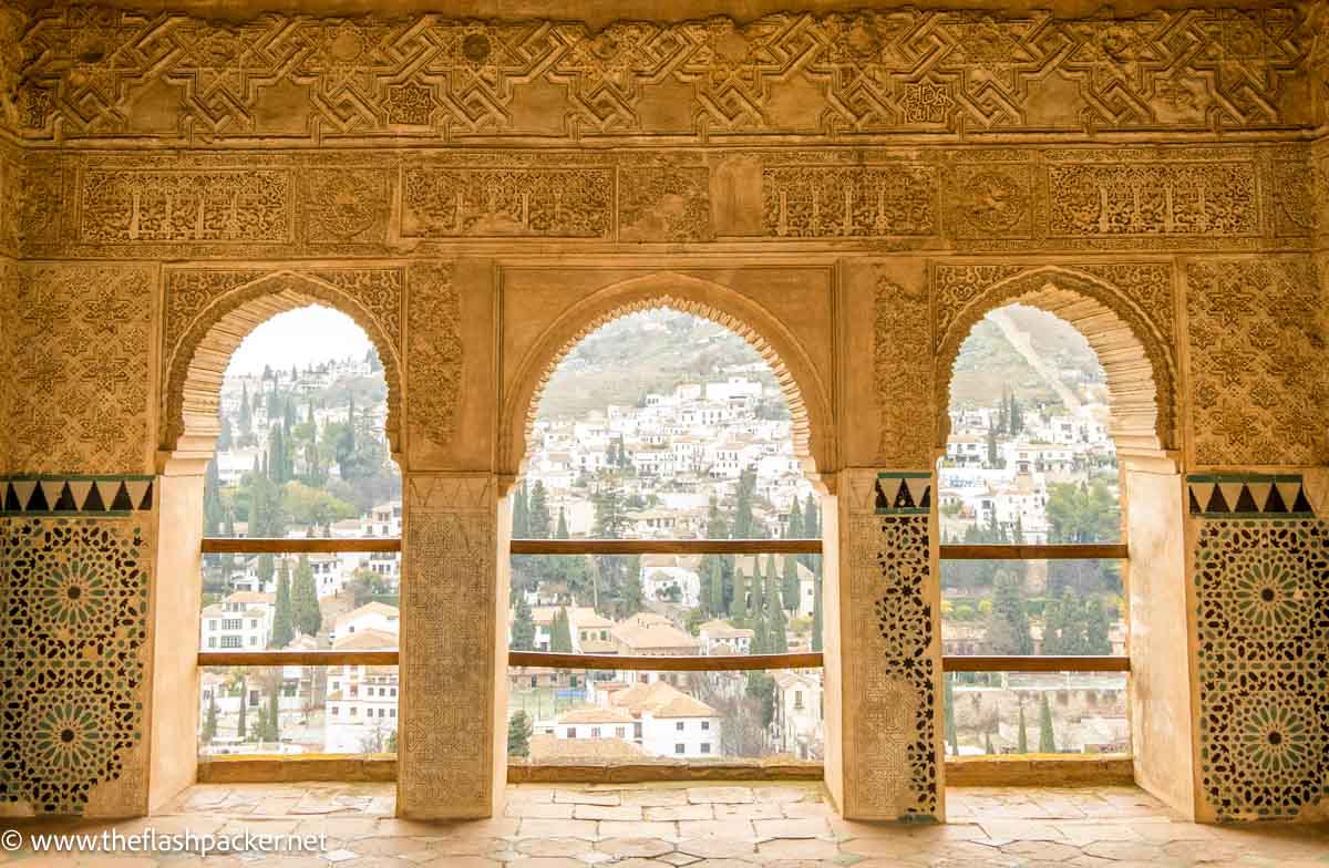 15 Insider Tips for Visiting the Alhambra, Granada (2025) 1 three beautifully carved islamic arches providing views of houses on hillside