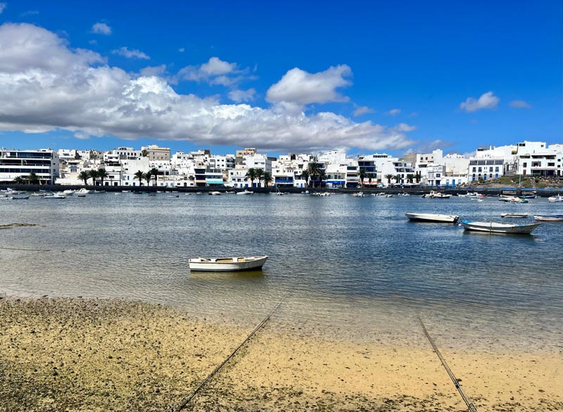 shallow lagoon with a few boats moored and lined by whitewashed buildings