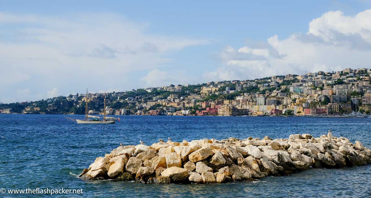 How to Spend a Day in Naples from a Cruise Ship 1 blue sea and sky with fishing boat and buildings lining shoreline seen during one day in naples