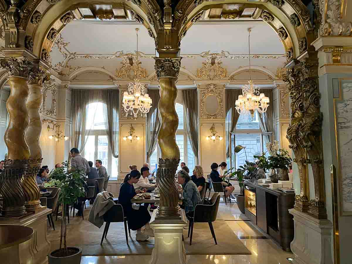 people dining in the ornate interior of new york cafe budapest seen through 2 arches