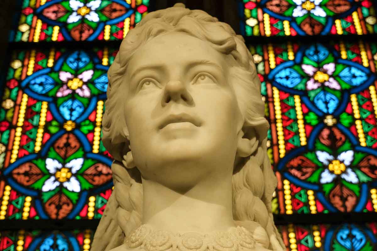statue of queen elisabeth of hungary next to stained glass window
