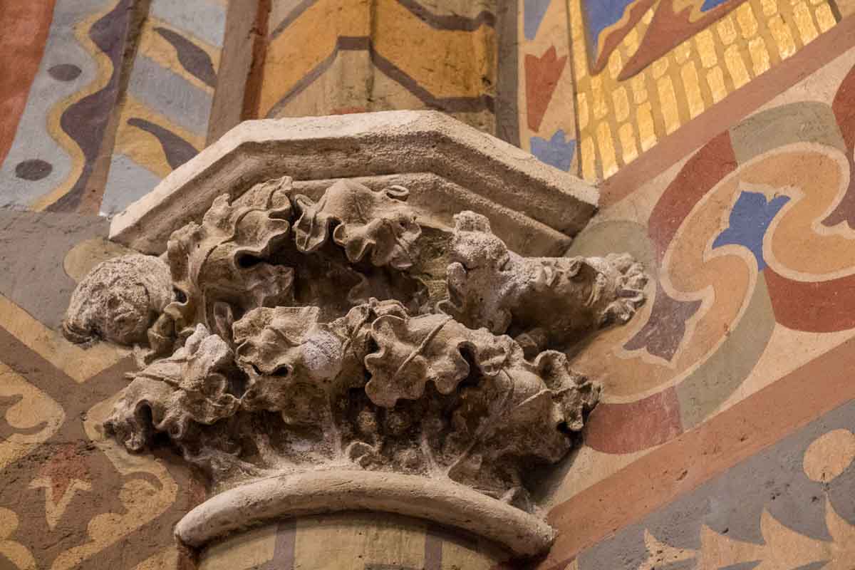 stone carvings on a stone column against a brightly painted wall