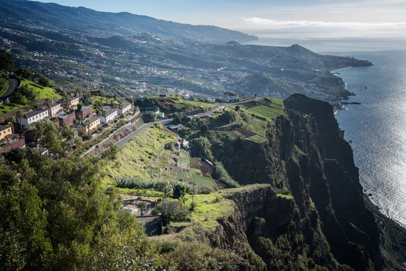 view from high cliff towards funchal in madeira with granite cliff face and ocean