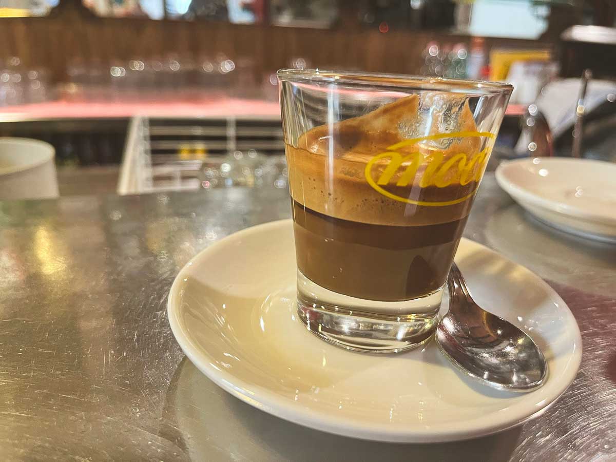 a caffe macchiato in a small glass on a saucer