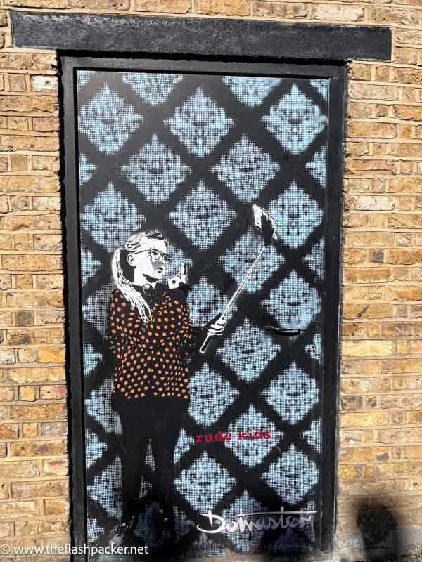 street art mural of a girl holding a finger up to a selfie stick