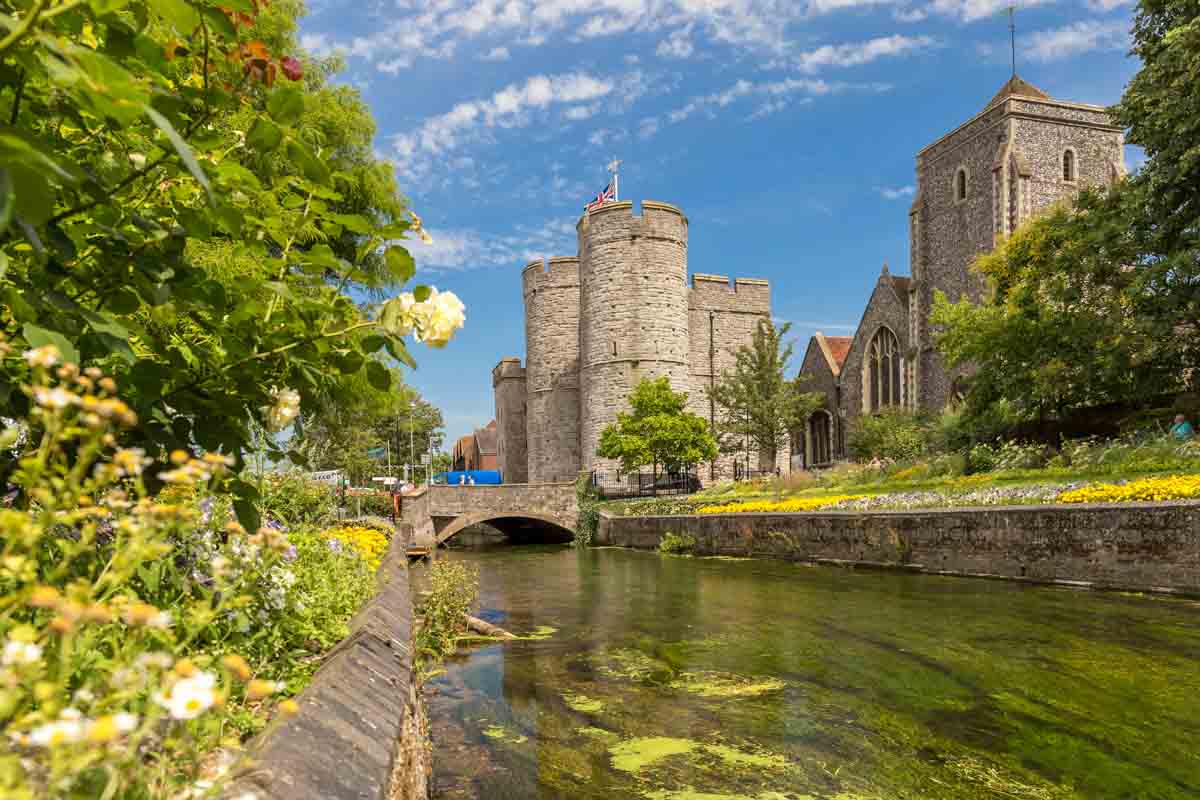 old stone buildings and 2 towers by side of river