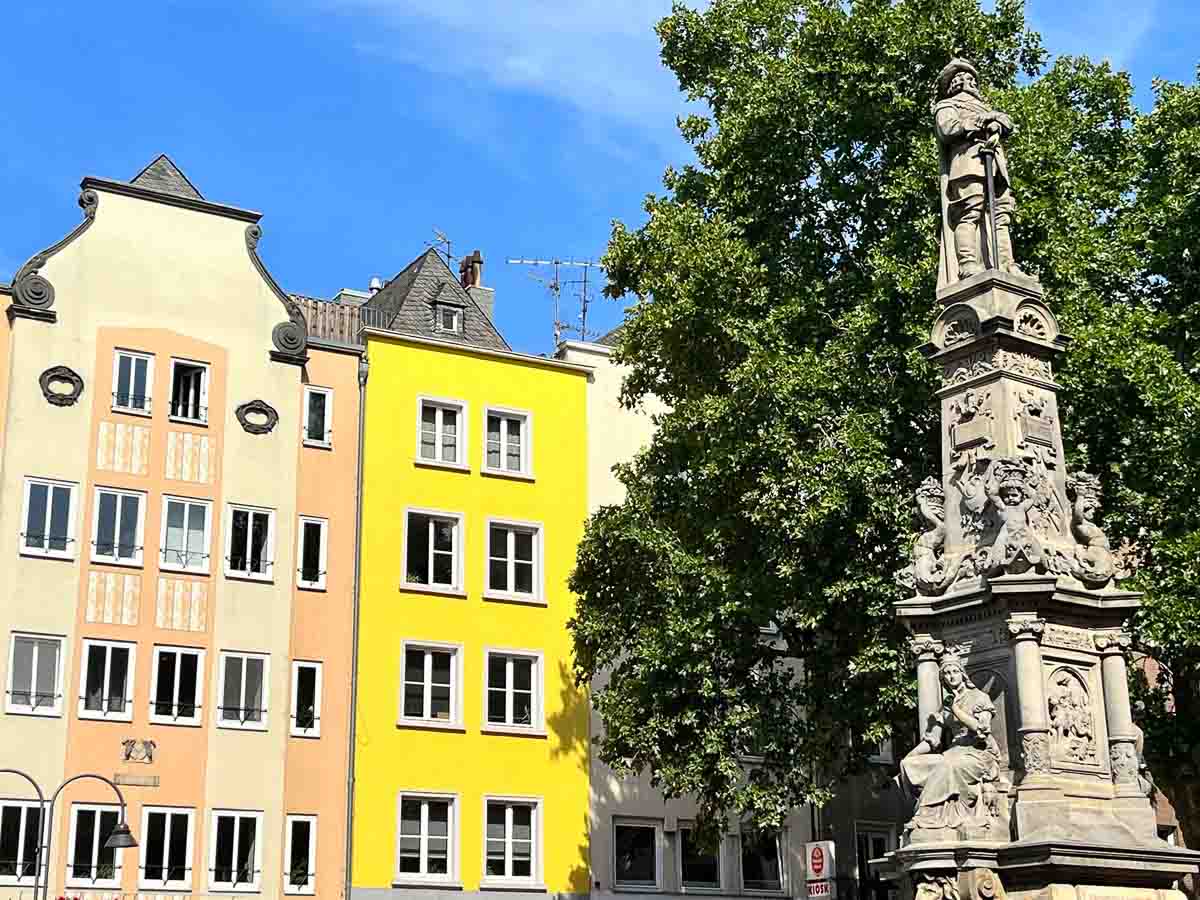 brightly coloured faux medieval buildings behind carved stone statues
