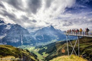 group of people standing on a platform looking at a spectacular alpine valley in switzerland