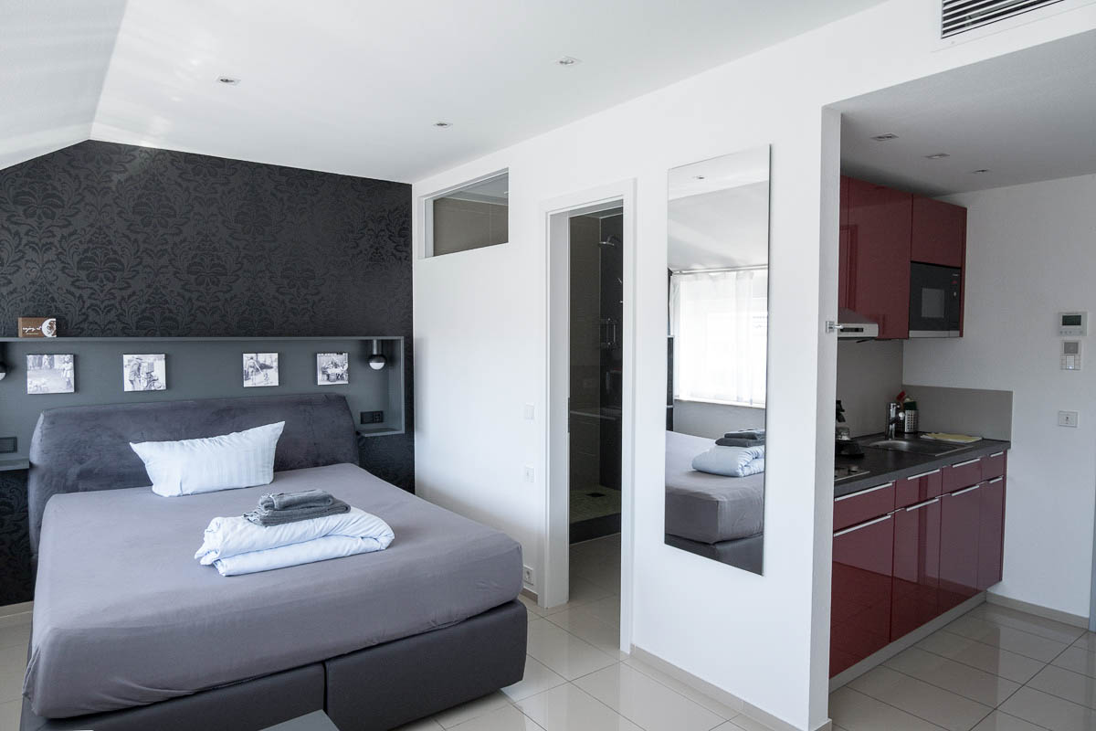 freiburg studio apartment with double bed with grey linen and small kitchen