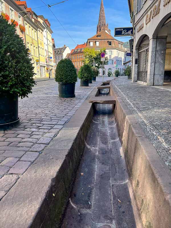 narrow dry water channel in street lined with some old buildings