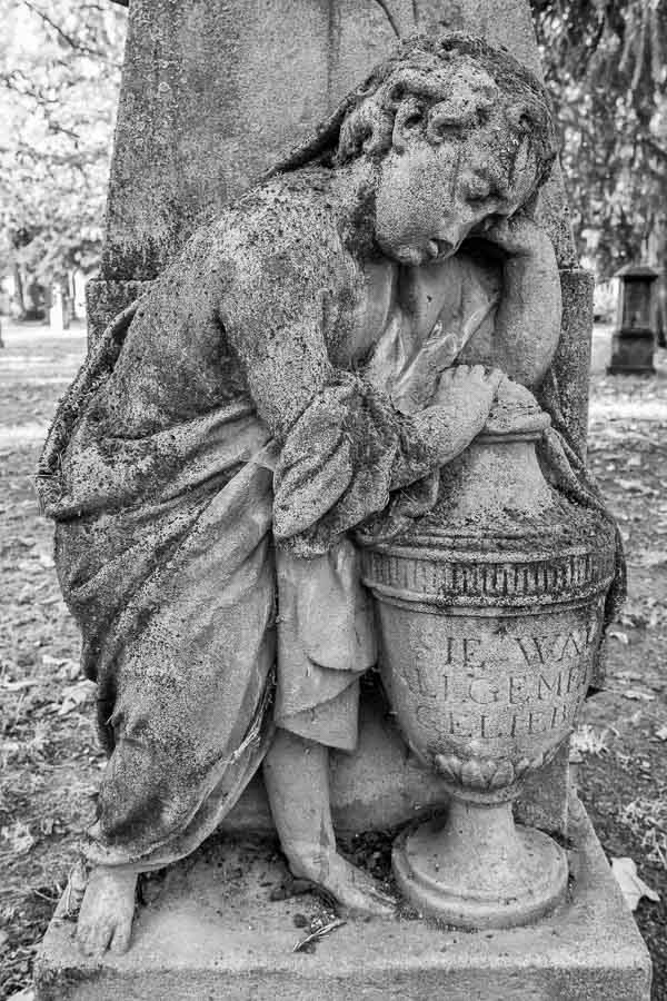 stone funerary sculpture of a sleeping angel next to an urn