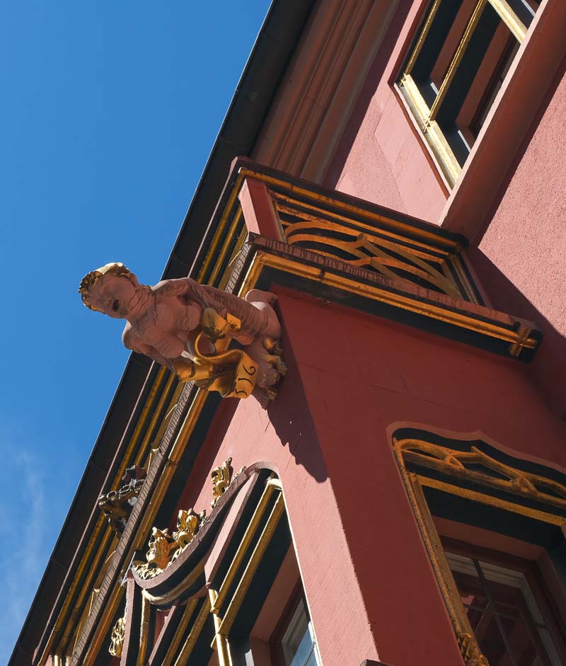 gargoyle hanging over salmon coloured building