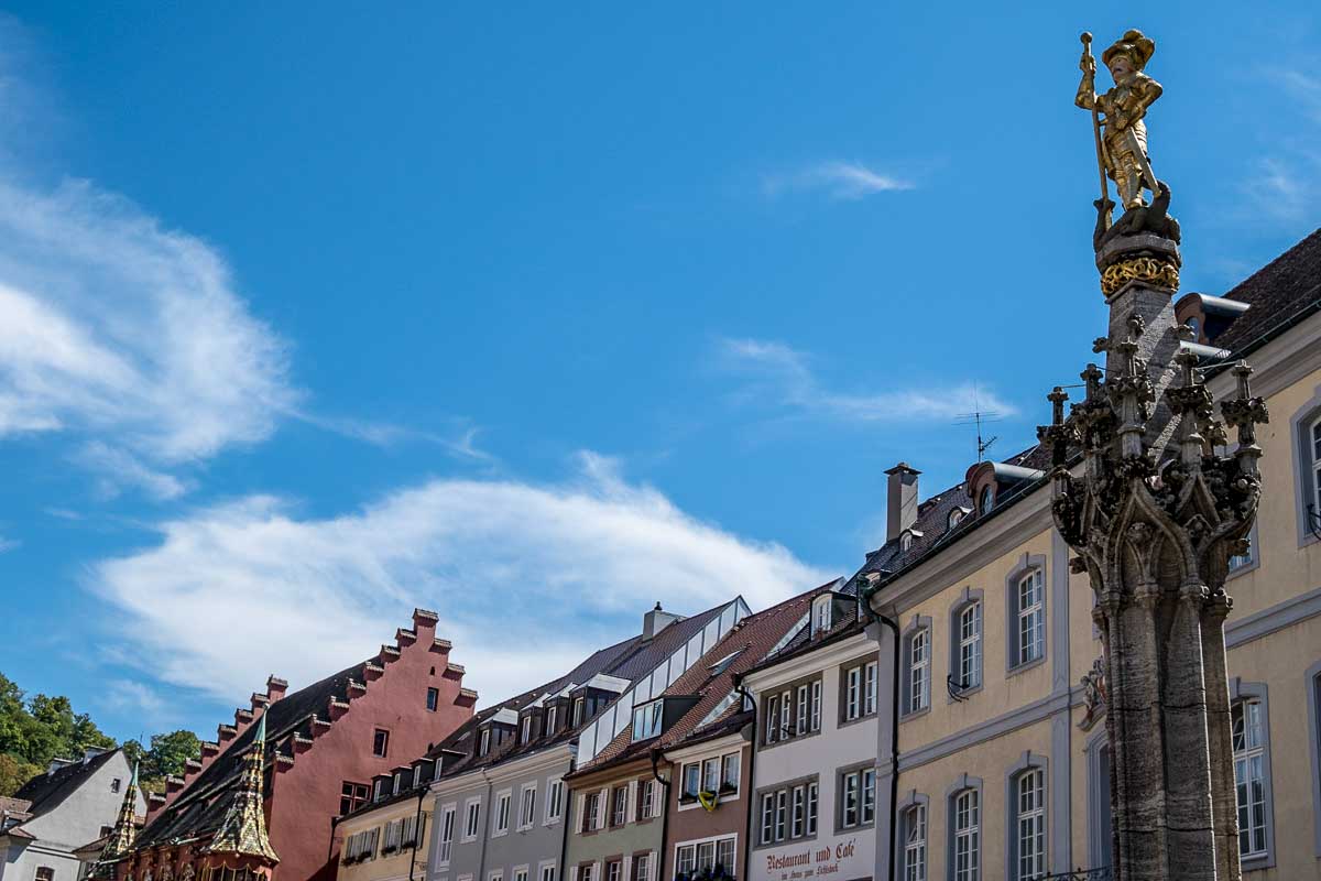 the top level of a row opf candy coloured medieval buildings in freiburg germany munsterplatz