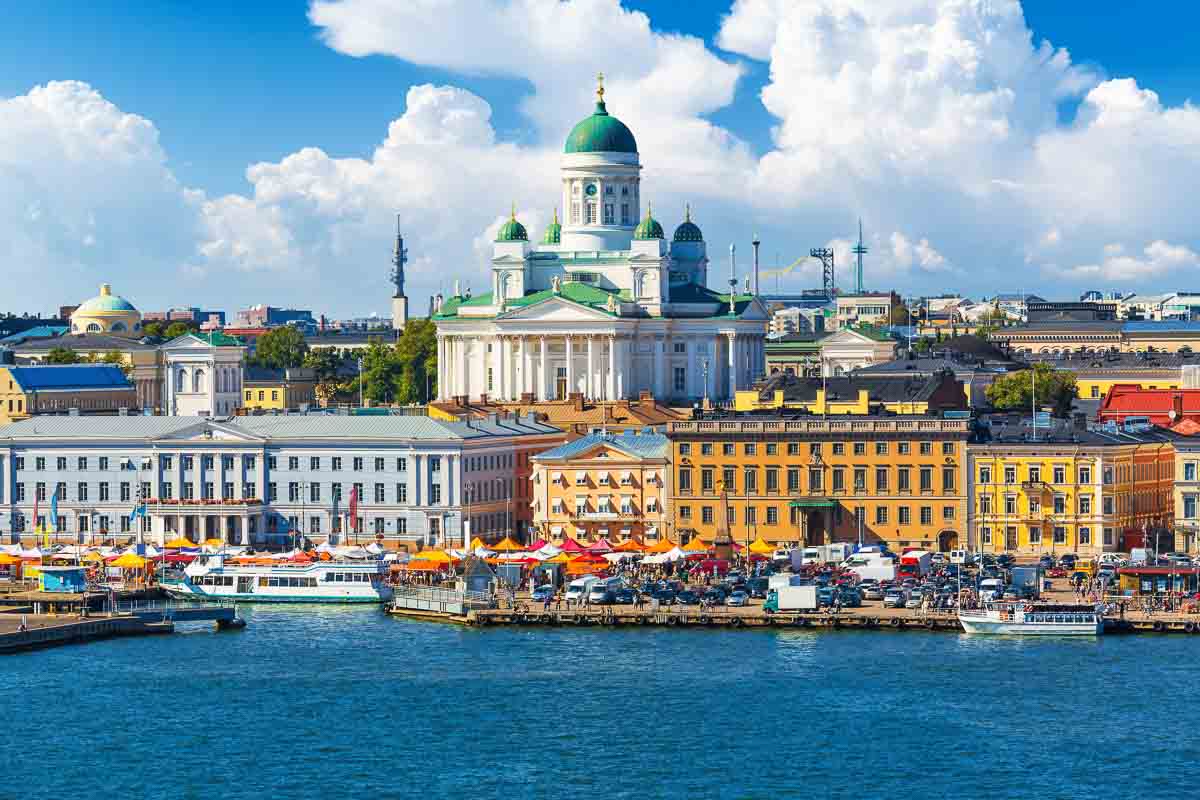 Finland 2 brightly colored buildings large white cathedral and boats along the seafront in helsinki finland