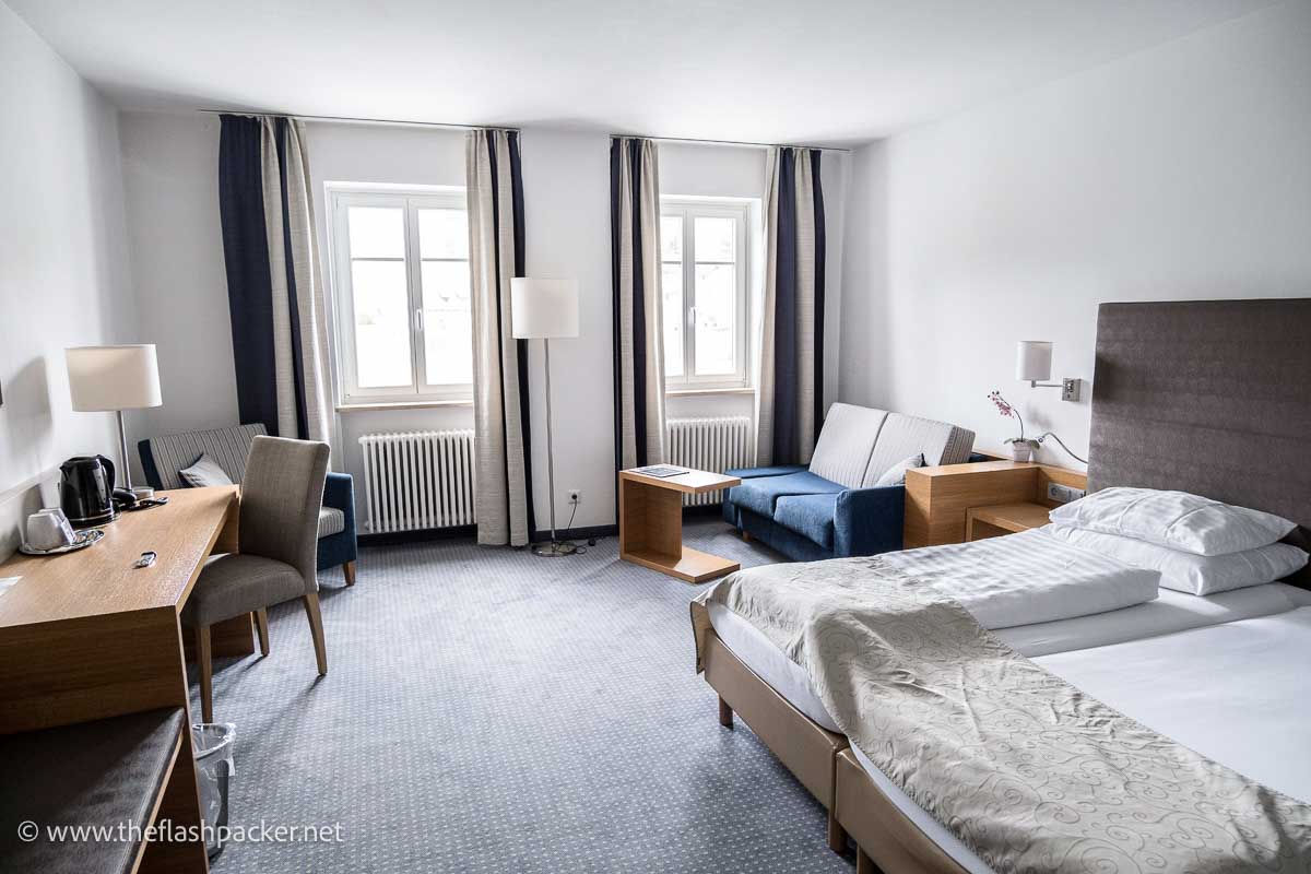 room at hotel altstadt passau with large bed sofas and chairs and a table