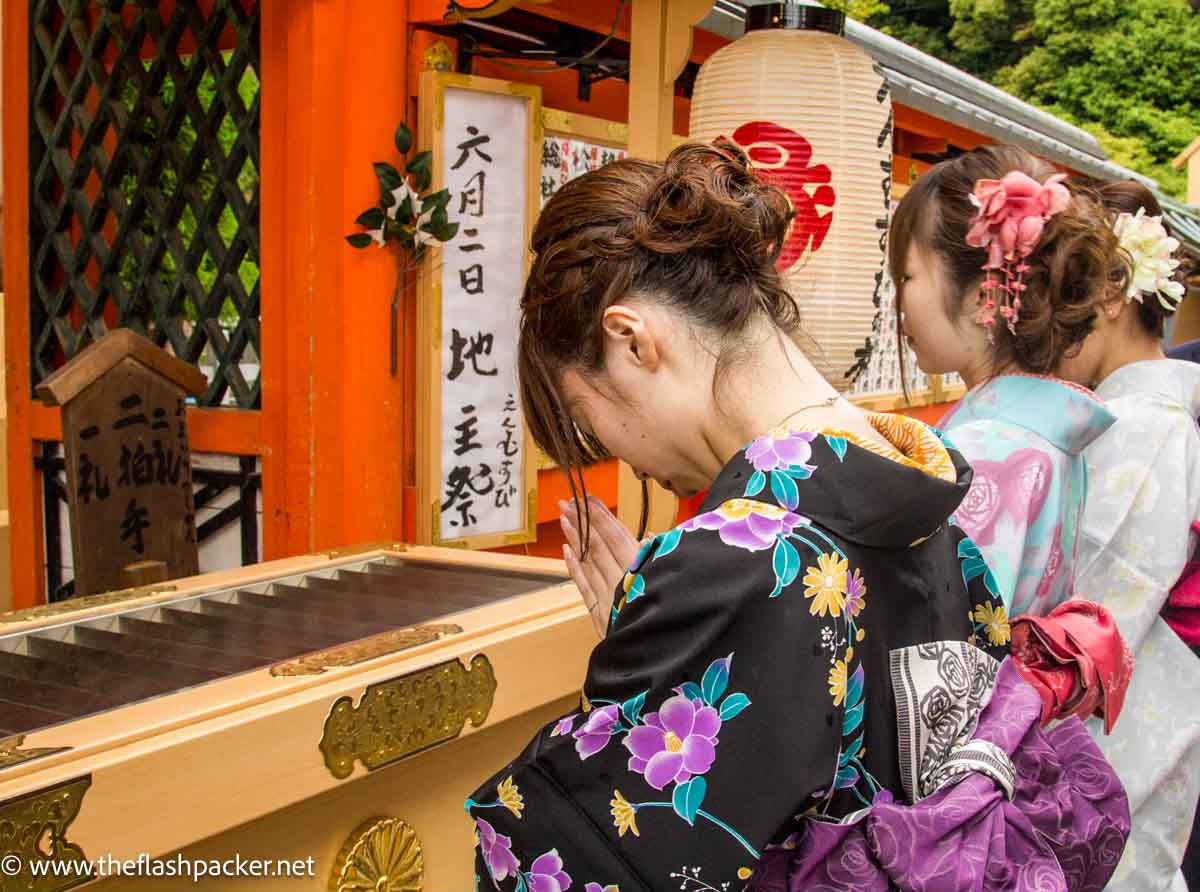 Japan 20 women dressed in kimonos praying at shrine at Kiyomizu-dera in kyoto japan