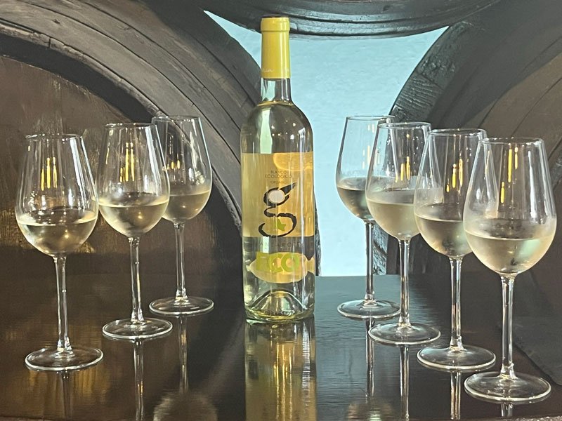 seven glasses of white wine on a reflecting table with the wine bottle in the middle