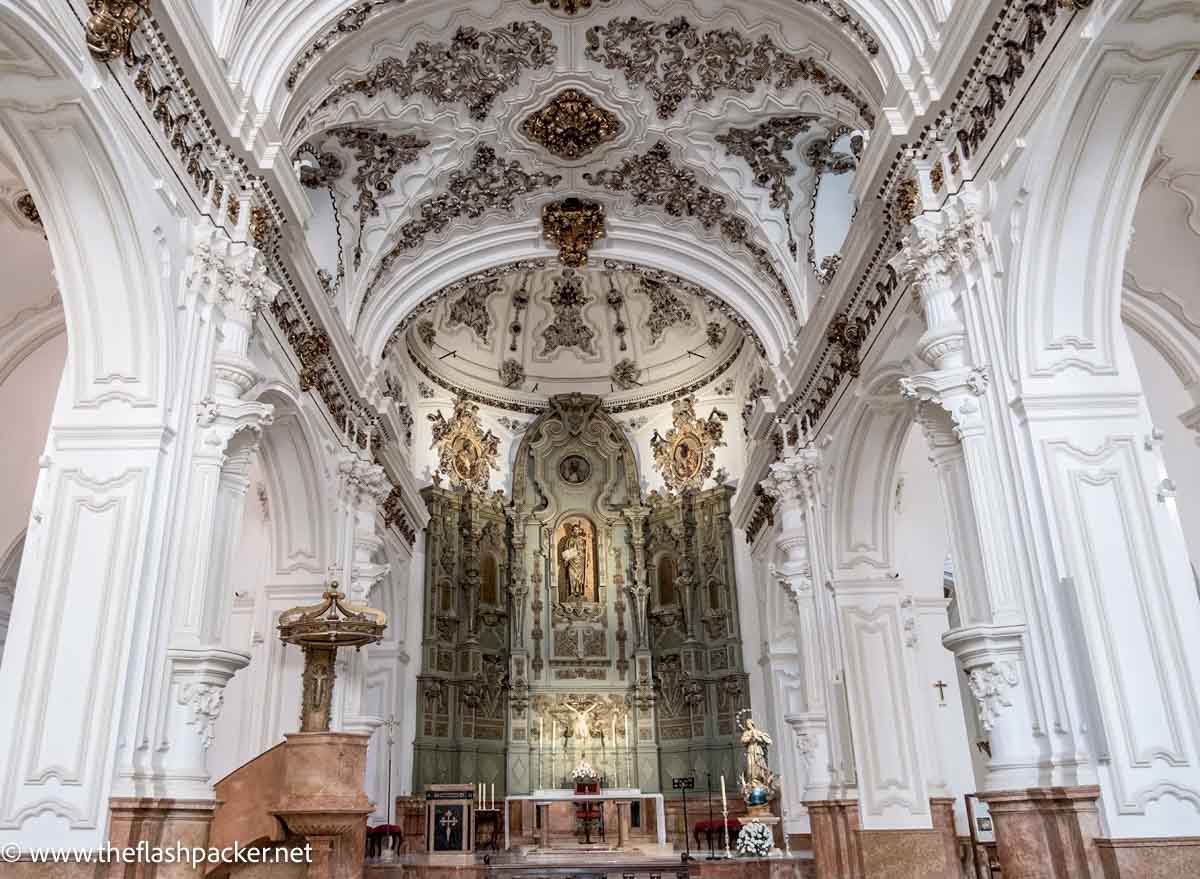 oprnate interior of baroque church with white pillars and altar