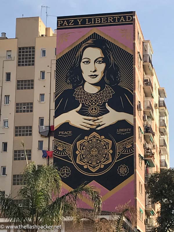 large wall mural in malaga spain of a woman with the words peace and libery