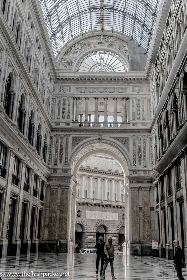 a few people walking in grand indoor gallery