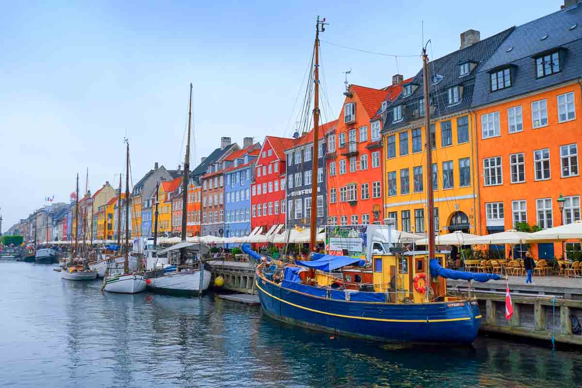 Denmark 2 brightly coloured housesd along the waterfront with boats in nyhavn