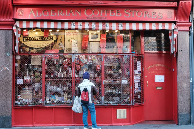 30 Famous Streets in London You'll Love (by a Local) 26 woman looking in wondow of coffee shop on old compton street which is one of londons most iconic streets