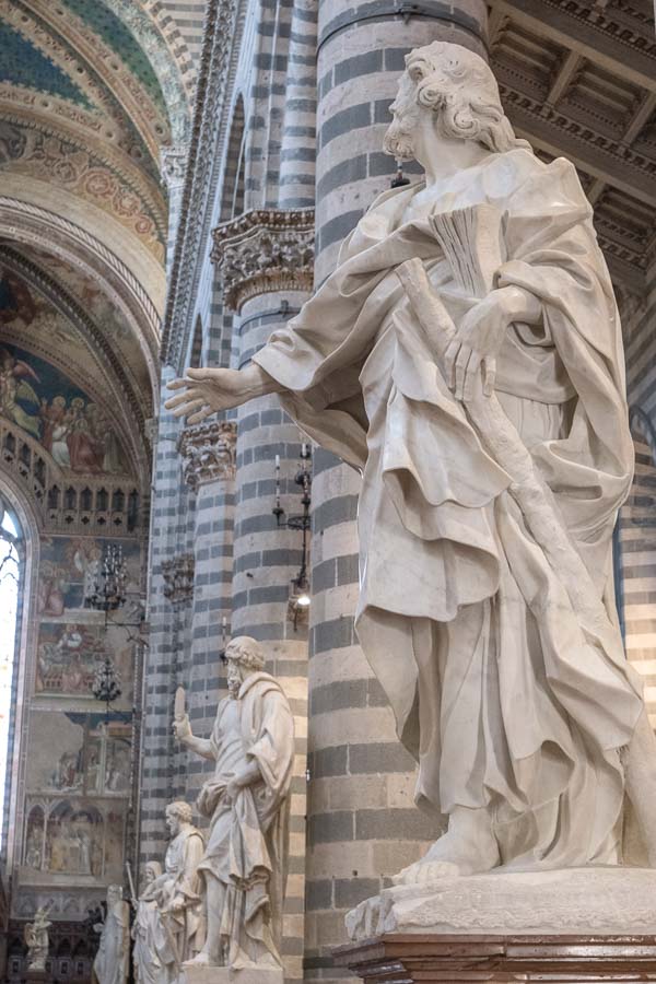 line of marble statues by striped columns along nave of orvieto duomo