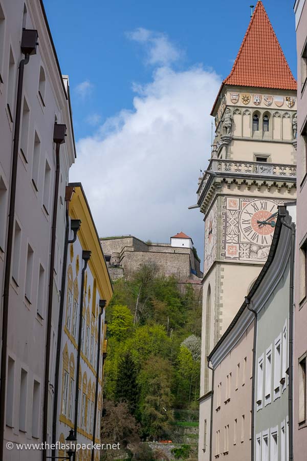 narrow street in passau altstadt with clock tower of church