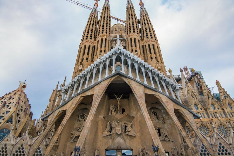 exterior of La Sagrada Familia Barcelona with 4 towers and carvings over doorway