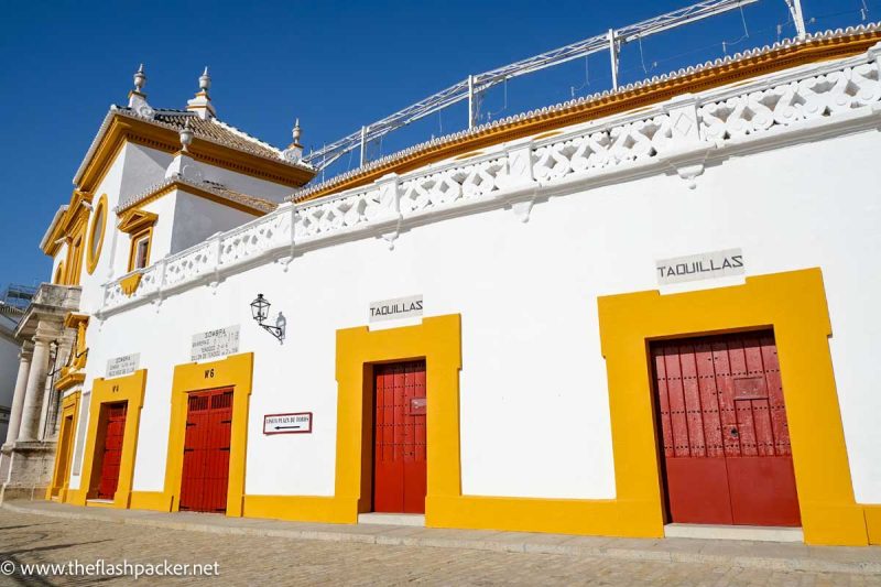 whitewashed exterior of bullring with red painted doors