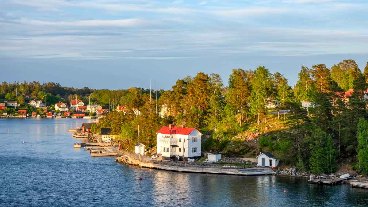 Sweden 2 white houses with red roofs on forested shoreline of stockholm's archipelago
