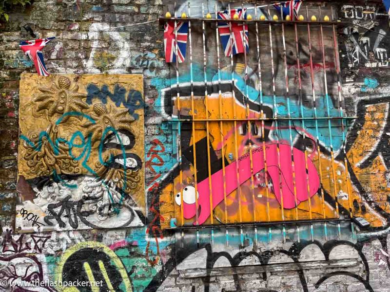a wall with graffiti and street art and union jack flags