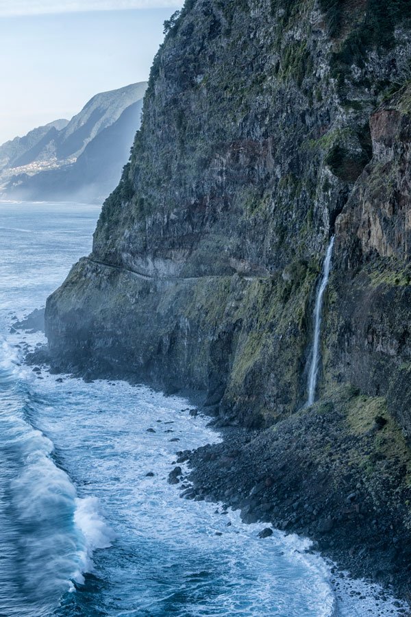 small waterfall tubling down a high cliff into the ocean