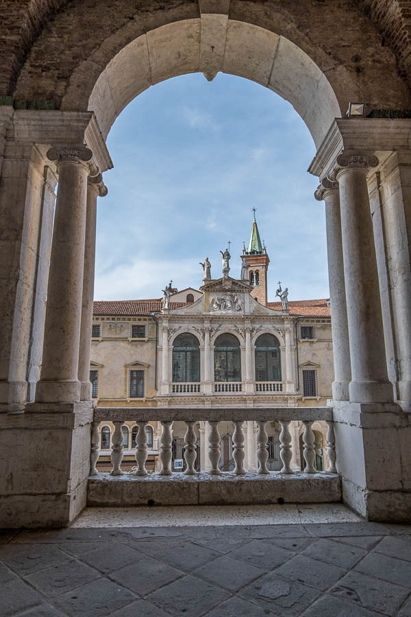 view of an old building in vicenza though an arch of the loggia of basilica palladio