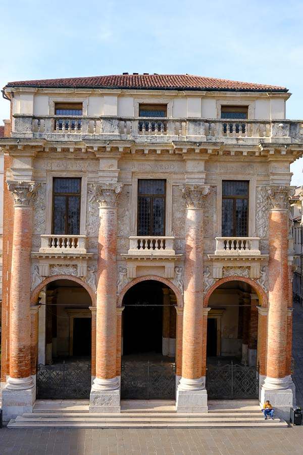 man sitting outside 3-story Loggia del Capitanato building in vicenza