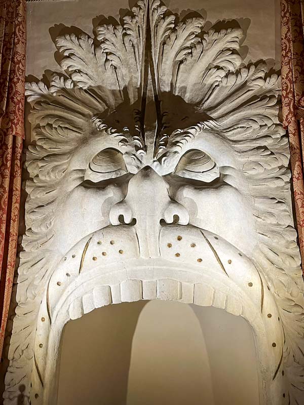 elaborate fireplace with stone sculpture of mythical beast with gaping mouth