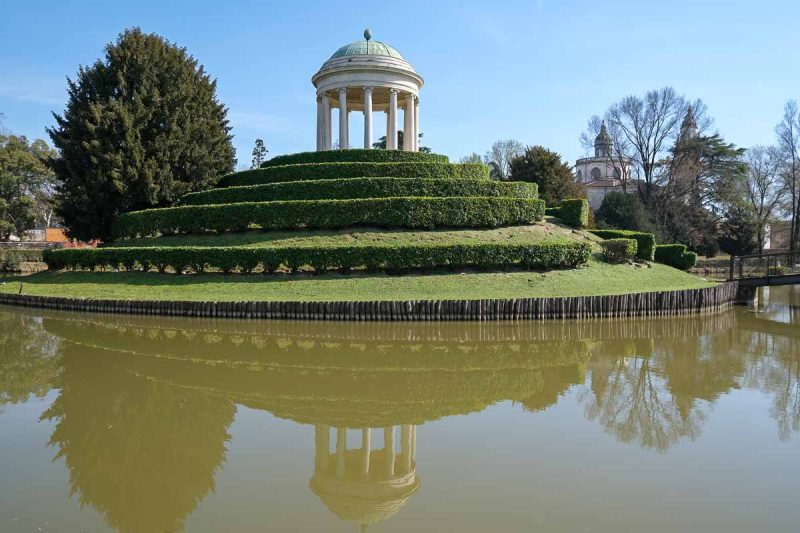 greek-style temple on an island in the middle of a pond