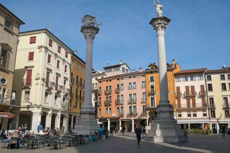 2 large columns in piazza dei signori in vicenza with people sitting at terrace cafe