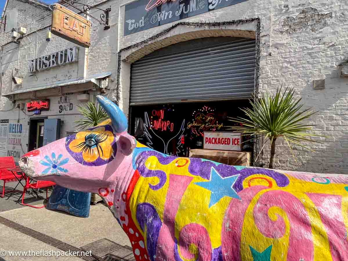Walthamstow, London: A Place Where Travellers Are Welcome 1 painted wooden cow outside the front of gods own junkyard in Walthamstow london